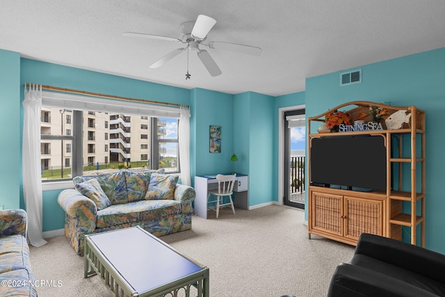 carpeted living room with a textured ceiling and ceiling fan