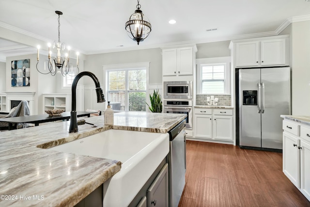 kitchen with a chandelier, stainless steel appliances, white cabinetry, and sink