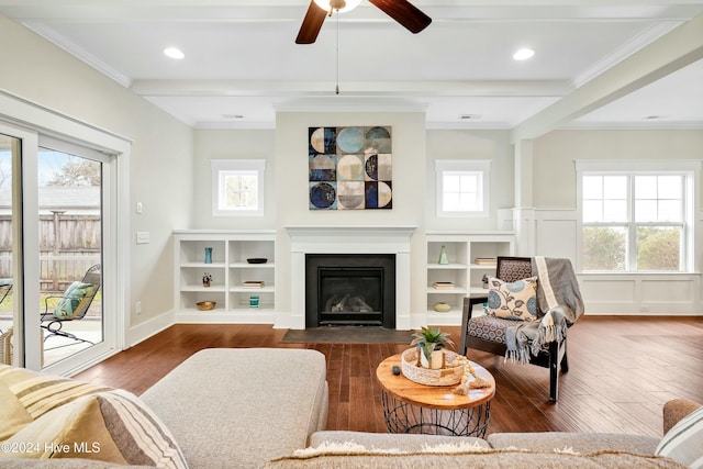 living room with a healthy amount of sunlight, dark hardwood / wood-style flooring, ornamental molding, and beam ceiling