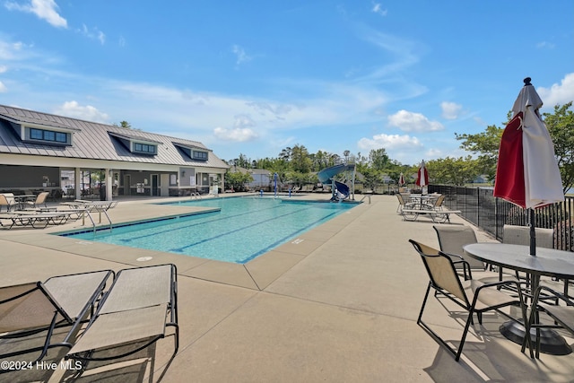 view of swimming pool with a water slide and a patio