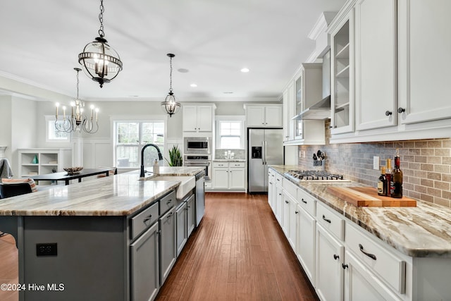 kitchen featuring a large island with sink, hanging light fixtures, white cabinets, and stainless steel appliances