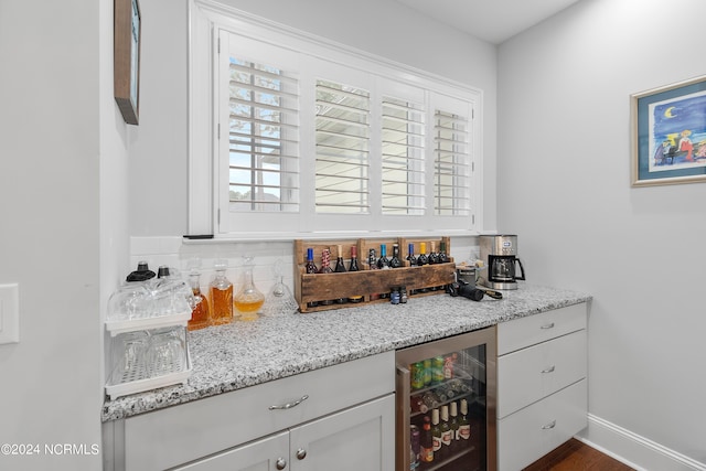 bar featuring wine cooler, light stone counters, and backsplash