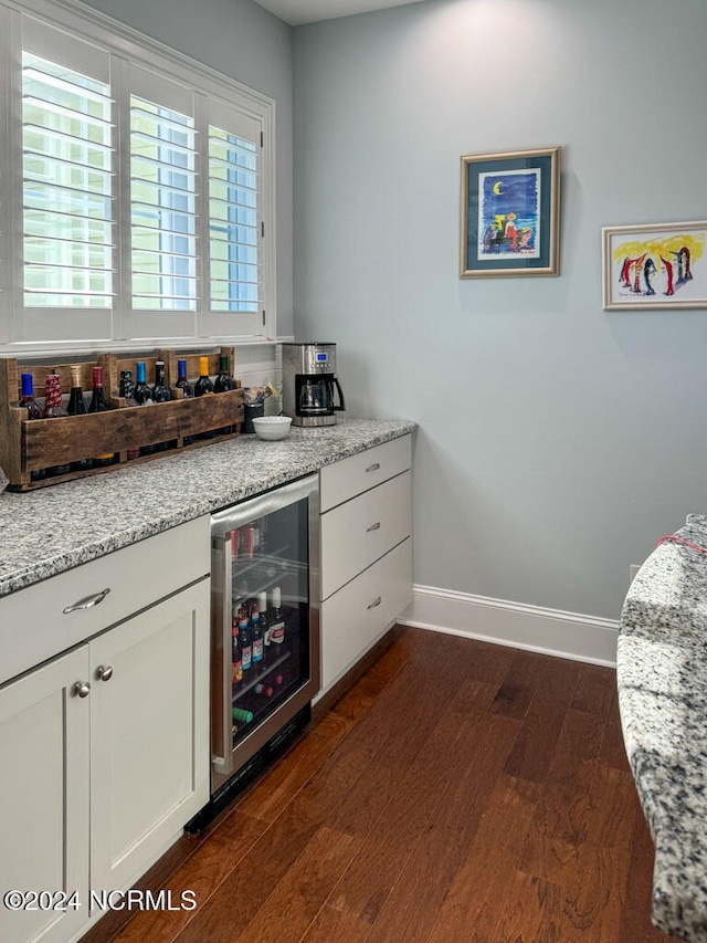 kitchen featuring dark hardwood / wood-style floors, light stone counters, and beverage cooler