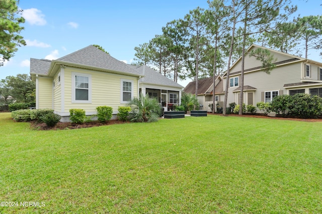 rear view of house featuring a yard and a sunroom