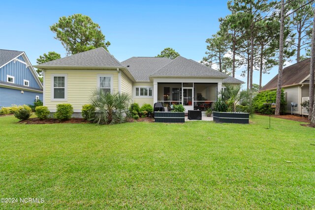 rear view of house featuring a sunroom and a lawn