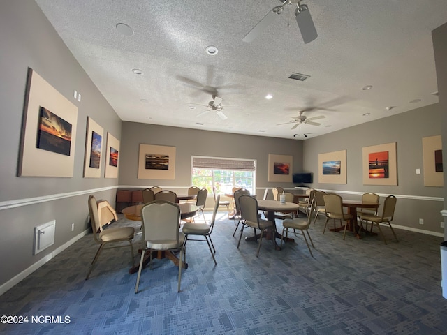 dining space featuring dark colored carpet, a textured ceiling, and ceiling fan