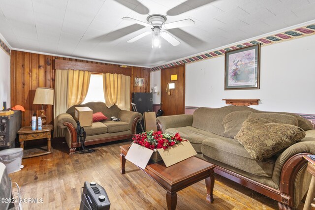 living room with ceiling fan, hardwood / wood-style flooring, and wood walls