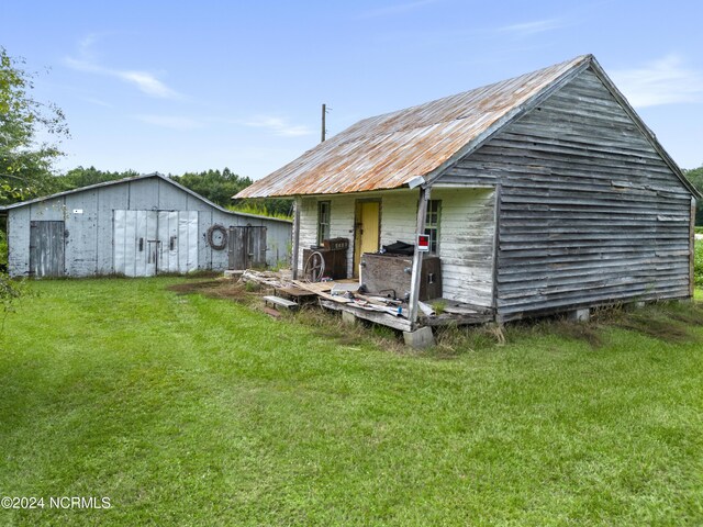 back of property with an outbuilding and a yard