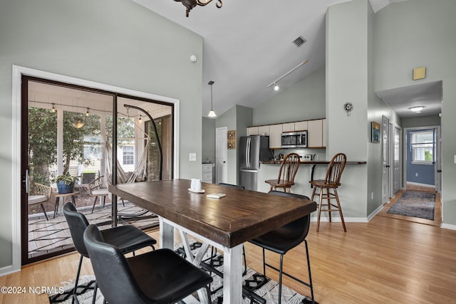 dining area with light hardwood / wood-style floors and high vaulted ceiling