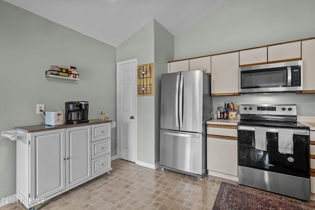 kitchen with appliances with stainless steel finishes, vaulted ceiling, and white cabinetry