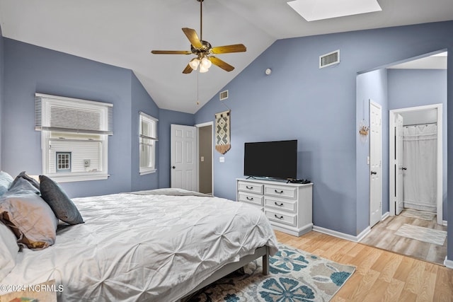 bedroom featuring ceiling fan, a closet, vaulted ceiling with skylight, and light hardwood / wood-style floors