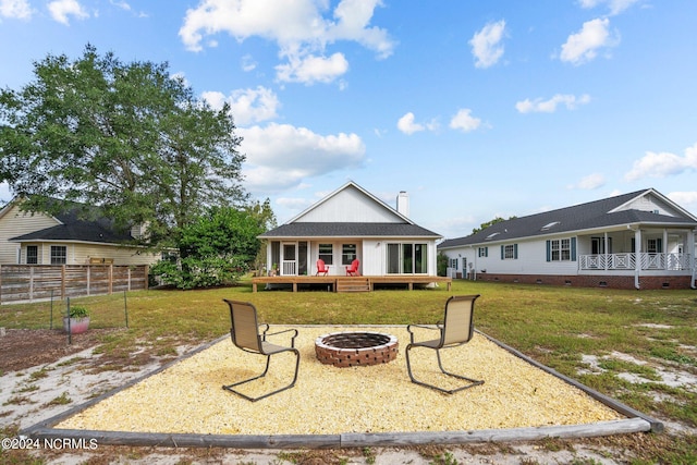 exterior space featuring a lawn, a wooden deck, and an outdoor fire pit