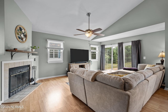 living room featuring light wood-type flooring, a tile fireplace, lofted ceiling, and ceiling fan