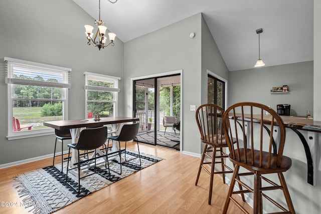 dining area with an inviting chandelier, light hardwood / wood-style floors, and high vaulted ceiling