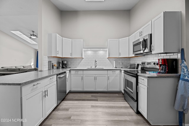 kitchen featuring ceiling fan, sink, kitchen peninsula, white cabinetry, and appliances with stainless steel finishes