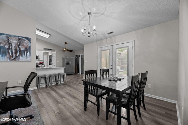 dining space with lofted ceiling, french doors, a textured ceiling, ceiling fan with notable chandelier, and hardwood / wood-style floors