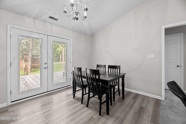 dining area with lofted ceiling, hardwood / wood-style floors, french doors, and a notable chandelier