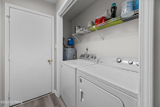 washroom featuring water heater, light hardwood / wood-style floors, and washer and dryer