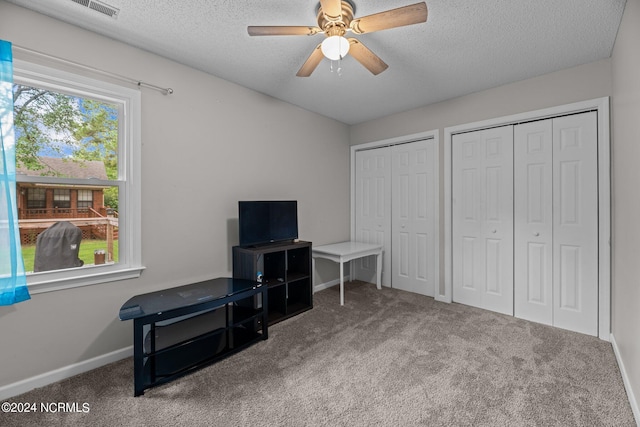 interior space with ceiling fan, carpet floors, and a textured ceiling