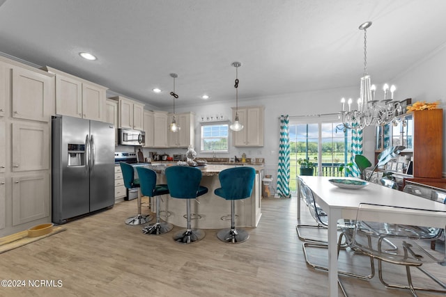 kitchen with a center island, hanging light fixtures, ornamental molding, light hardwood / wood-style floors, and stainless steel appliances