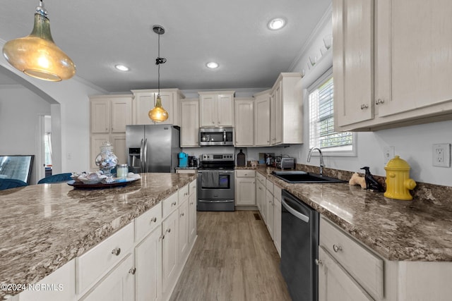 kitchen with light hardwood / wood-style floors, pendant lighting, stainless steel appliances, and ornamental molding