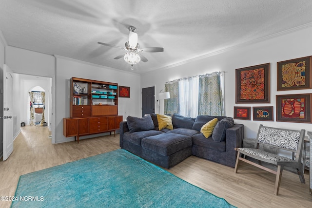 living room featuring a textured ceiling, light hardwood / wood-style floors, ceiling fan, and crown molding