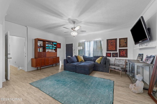 living room featuring ceiling fan, light hardwood / wood-style flooring, a textured ceiling, and ornamental molding