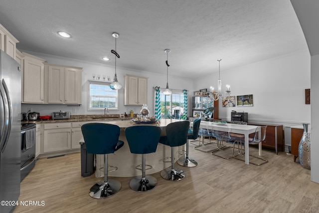 kitchen with cream cabinets, sink, pendant lighting, and light wood-type flooring