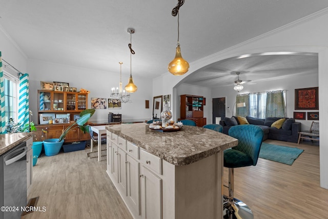 kitchen with dishwasher, crown molding, pendant lighting, a kitchen bar, and light wood-type flooring