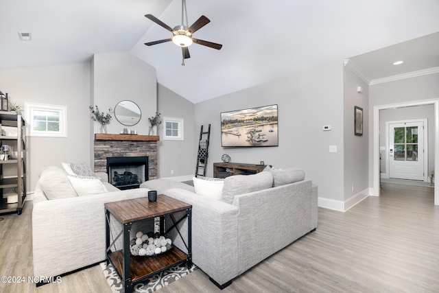 living room with ceiling fan, a stone fireplace, light hardwood / wood-style floors, and a wealth of natural light