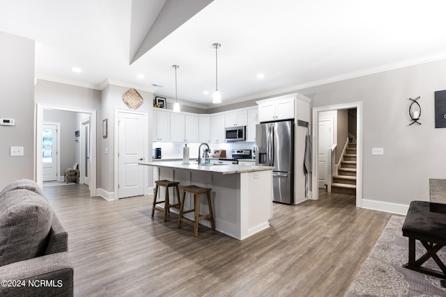 kitchen with white cabinets, a kitchen island with sink, appliances with stainless steel finishes, a breakfast bar, and light hardwood / wood-style floors