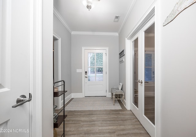 entryway with light wood-type flooring, ornamental molding, and french doors