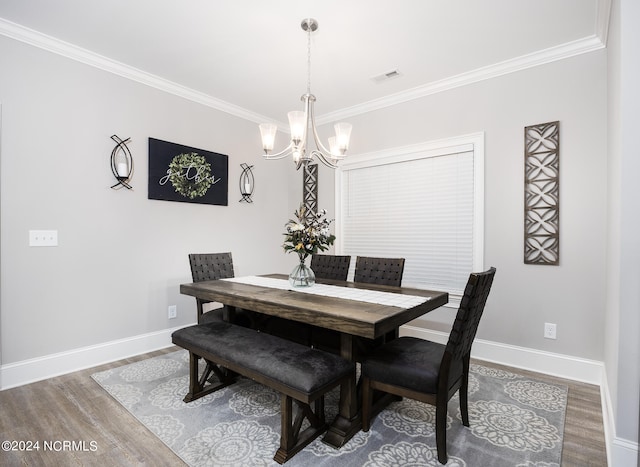 dining space with ornamental molding, hardwood / wood-style floors, and a chandelier