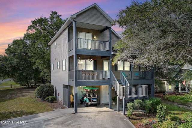 view of front of property featuring a balcony, covered porch, stairs, concrete driveway, and a carport