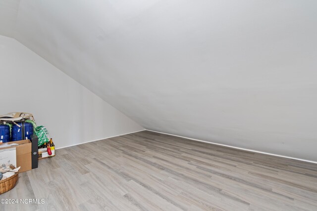 additional living space featuring light wood-type flooring and vaulted ceiling