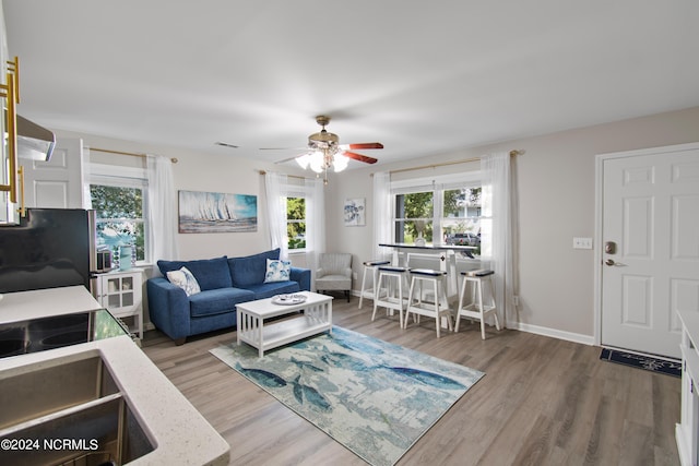 living room featuring wood finished floors, a ceiling fan, baseboards, and visible vents
