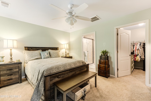 bedroom with a closet, a walk in closet, ceiling fan, and light colored carpet