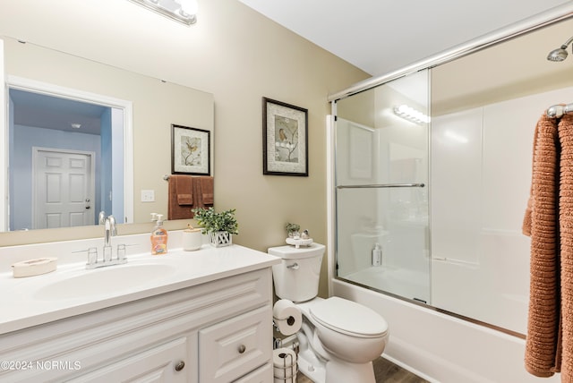 full bathroom featuring wood-type flooring, combined bath / shower with glass door, vanity, and toilet