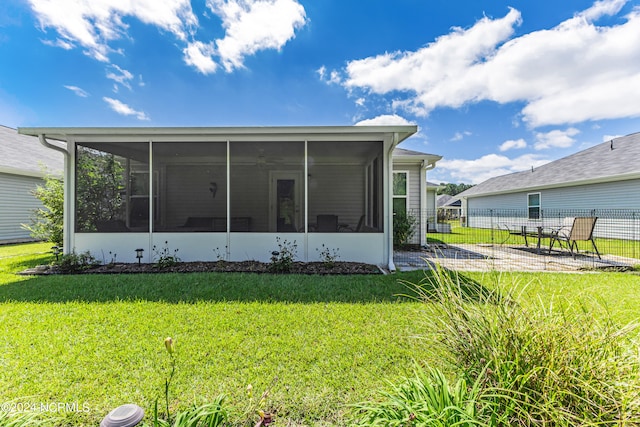 rear view of house with a sunroom and a lawn