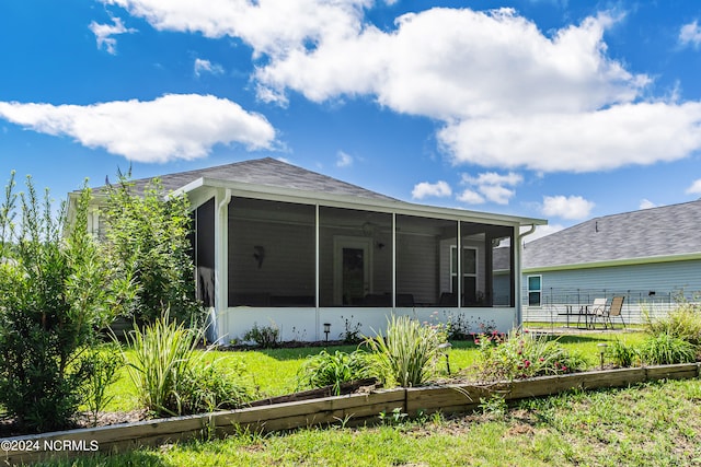 rear view of property with a sunroom and a yard