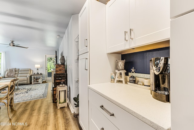 kitchen with light wood-type flooring, white cabinetry, and ceiling fan