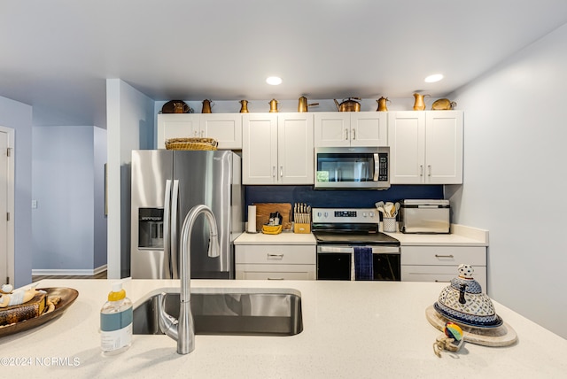 kitchen featuring tasteful backsplash, sink, stainless steel appliances, and white cabinets