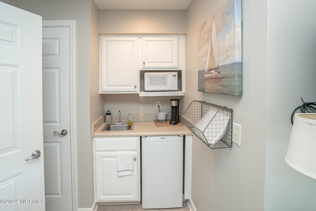 kitchen with white appliances, white cabinetry, and sink