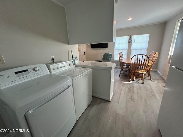 clothes washing area featuring crown molding, light hardwood / wood-style floors, and washing machine and clothes dryer