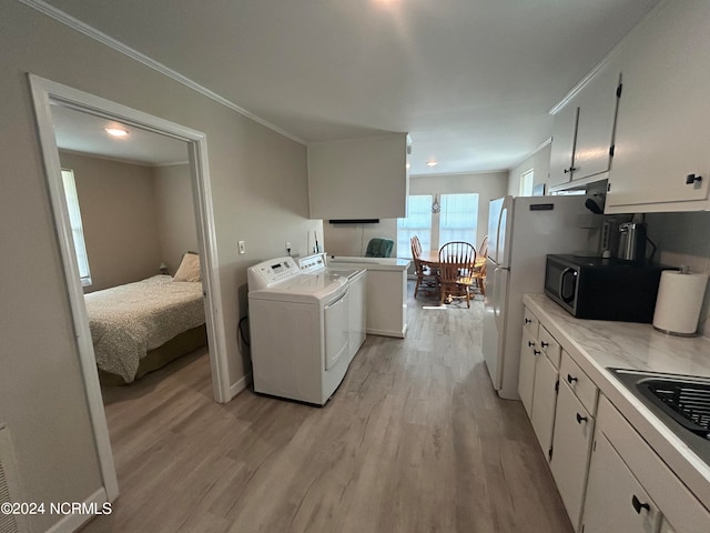 clothes washing area with light hardwood / wood-style floors, separate washer and dryer, and crown molding