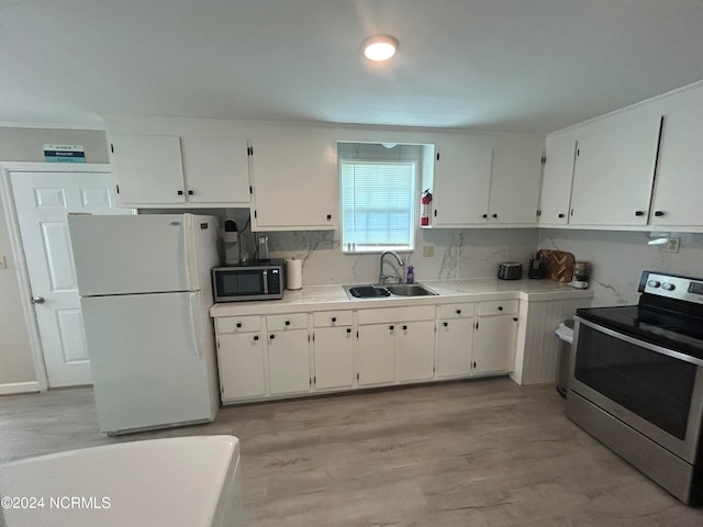 kitchen with sink, backsplash, white cabinetry, appliances with stainless steel finishes, and light hardwood / wood-style floors