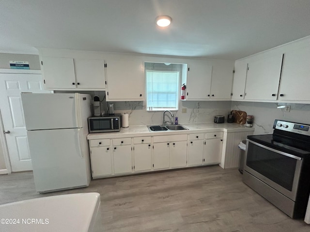 kitchen with white cabinets, sink, tasteful backsplash, stainless steel appliances, and light hardwood / wood-style floors