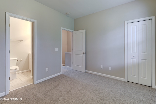 unfurnished bedroom featuring light colored carpet, a closet, and ensuite bathroom