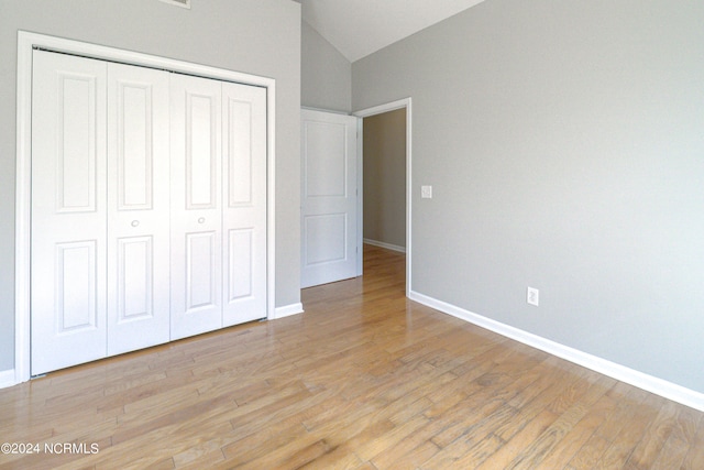 unfurnished bedroom featuring lofted ceiling, light hardwood / wood-style flooring, and a closet