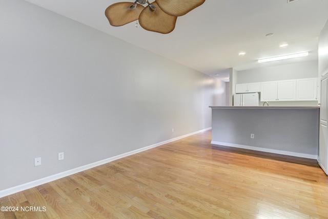 empty room with ceiling fan and light hardwood / wood-style flooring